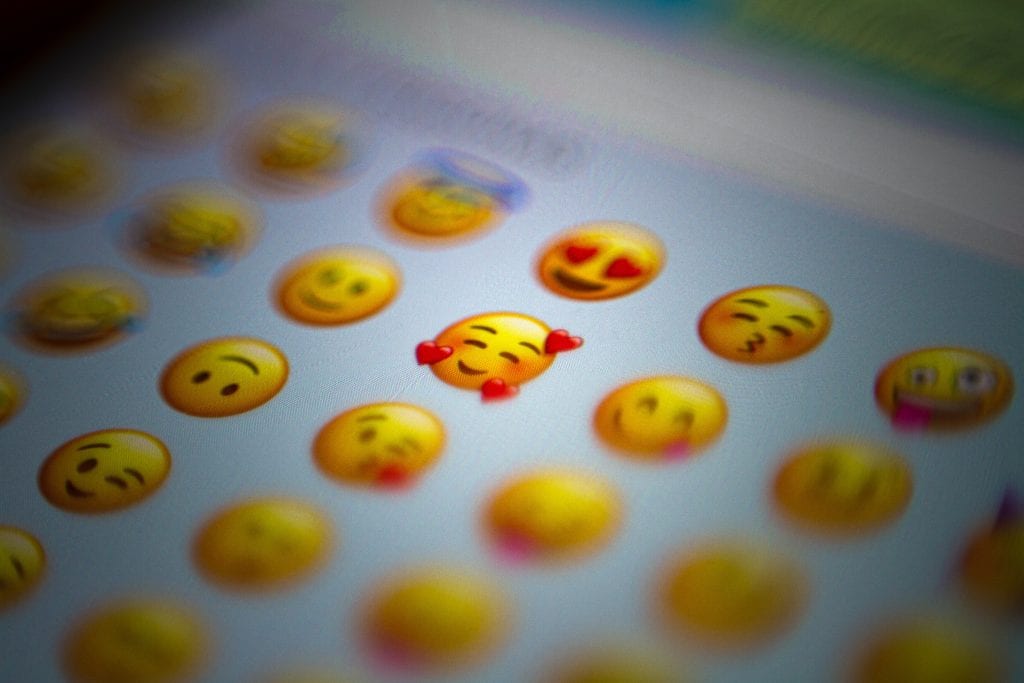 Emoji faces on a mobile phone, how can emojis be used on your business social media.